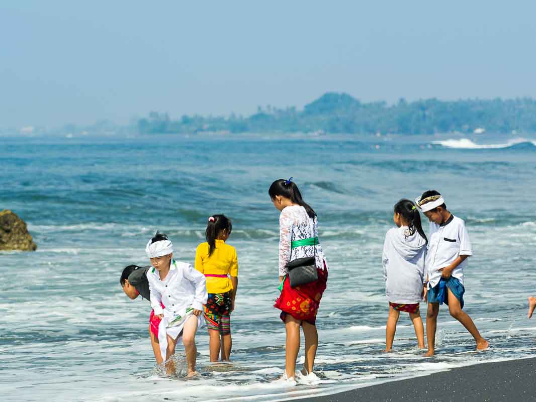 海岸でお清めをする少年少女