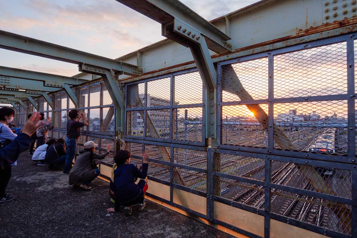 三鷹の跨線橋から夕陽を眺める人々